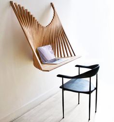 a chair and desk in front of a wall with a wooden sculpture on it's side