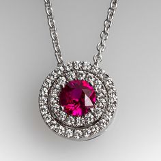 This gorgeous ruby pendant necklace is centered with one (1), prong set, round cut natural ruby and bordered with a double halo setting accented with thirty-nine (39), prong set, round brilliant cut diamonds. The pendant measures 9.8mm in diameter and 5.3mm thick. The pendant is suspended from an eighteen karat white gold cable link style neck chain measuring 16-1/2 inches in length. Signed Spark. Luxury Ruby Jewelry With Pave Setting, White Gold Ruby Necklaces With Brilliant Cut, White Gold Ruby Necklace With Brilliant Cut, Ruby Necklace With Brilliant Cut, Brilliant Cut Ruby Necklace In Round Shape, Formal Ruby Necklace With Halo Setting, Fine Jewelry Round Pendant Necklace With Center Stone, Formal Ruby Jewelry With Pave Setting, White Gold Necklaces With Round Center Stone