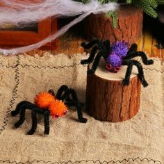 two fake spider figurines sitting on top of a piece of wood