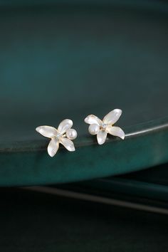 Embrace the beauty of simplicity with our White Lilac Flower Enamel Earring Studs, delicately decorated with a freshwater pearl and a sparkling zircon. These tiny yet elegant earrings capture the essence of purity and innocence, symbolized by the white lilac flower. Formal White Sterling Silver Flower Earrings, White Feminine Earrings With Flower Decoration, Delicate Pearl White Flower Pearl Earrings, White Flower Shaped Sterling Silver Earrings, White Flower-shaped Sterling Silver Earrings, White Flower Sterling Silver Earrings, White Pearl Flower Earrings For Formal Occasion, White Petal-shaped Jewelry With Flower Charm, White Sterling Silver Flower Earrings