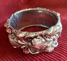 This is a gorgeous unsigned hinged or clamper bracelet, most likely by Whiting and Davis.  While unmarked, it is believed to be Whiting and Davis because when this bracelet was sold as part of an earring/bracelet set, the bracelets did not carry the Whiting and Davis mark.  It has a striking and ornate repousse art nouveau design and is a big, bold bracelet at 1 1/4" wide while also bringing a delicate touch at the same time with the beautiful design.  This bracelet is sure to bring that special touch to any summer outfit!  A statement bracelet also makes a perfect gift and its timeless style will appeal to so many!  The bracelet has a push-in clasp but it is missing the safety chain.  There is a place for it;  you could easily take it to a jeweler or purchase one and attach it yourself. Luxury Antique Silver Vintage Cuff Bracelet, Vintage Cuff Bracelet With 17 Jewels For Formal Occasions, Antique Evening Bracelets, Antique Cuff Bracelet For Formal Occasions, Victorian Hinged Cuff Bangle Bracelet, Victorian Hinged Bangle Bracelets, Victorian Hinged Cuff Bracelet, Victorian Style Metal Clip-on Jewelry, Antique Hallmarked Cuff Bracelet For Formal Occasions