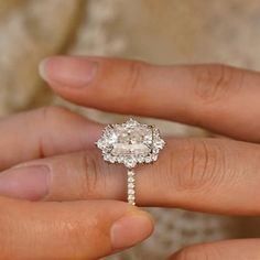 a close up of a person's hand holding an engagement ring