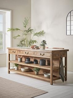 a wooden table with pots and plants on it next to a potted plant in front of a window