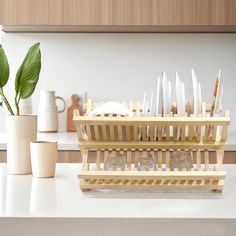 a wooden rack holding knives on top of a counter next to cups and vases