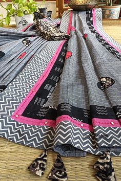 This exquisite handloom saree exudes a sense of understated elegance and contemporary charm. Crafted from pure, lightweight cotton, it presents a harmonious blend of colors and intricate detailing, making it a versatile choice for various occasions, particularly ideal for the upcoming festive season. The dominant shade of this saree is a steel grey, reminiscent of sophistication and modernity. The body of the saree is adorned with delicate zari checks, which glisten with a subtle opulence. What Unstitched Cotton Saree, Unstitched Cotton Fabric For Festivals, Handloom Cotton Fabric For Festivals, Festive Unstitched Cotton Saree, Multicolor Cotton Handloom Saree, Handloom Multicolor Cotton Saree, Multicolor Cotton Saree With Block Print, Cotton Dupatta With Printed Border, Cotton Dupatta With Printed Motifs