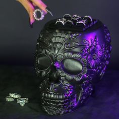 a woman's hand reaching into a skull shaped container with purple lighting on it