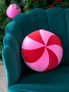 a green chair with a pink and red candy cane pillow on it's back