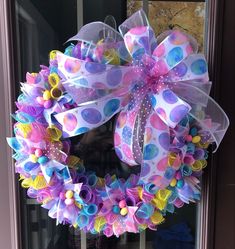 a colorful wreath on the front door with polka dots and ribbons hanging from it's side