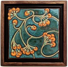 an art work with orange flowers and leaves on blue background, framed in wooden frame