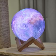 the moon lamp is sitting on top of a wooden stand