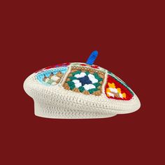 a crocheted white hat with multicolored patches on the front and sides