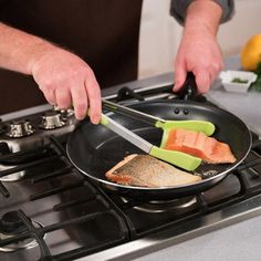 a man is cooking salmon in a frying pan on the stove top with a knife