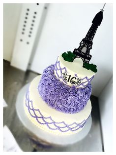 a three tiered cake with the eiffel tower in the middle on top