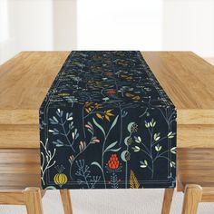 a wooden table topped with a black and yellow floral print table runner on top of it