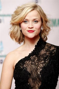 a woman with blonde hair wearing a black dress and red lipstick is posing for the camera