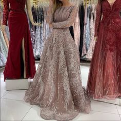 a woman standing in front of two dresses on mannequins at a store