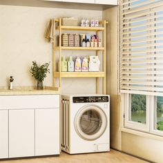 a washer sitting next to a dryer in a room with white cabinets and windows