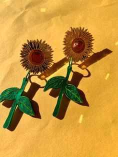 two sunflower brooches sitting on top of a table