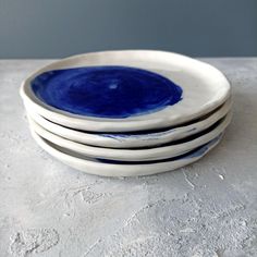 four blue and white plates stacked on top of each other in front of a gray wall