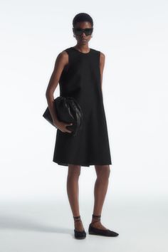 This simple mini dress rings true to the considered design ethos at COS. Offered in a perennial black hue, it's styled in a clean A-line silhouette and has an enthraling twist detail that frames the V-back. It is crafted from a TENCEL™ Lyocell and linen blend that's light in balmy weather. Relaxed fitSide seam pocketsTENCEL™ is a trademark of Lenzing AG. TENCEL™ Lyocell is made from renewable wood sources, using a process that recycles 99% of all chemicals and water  Shell: 77% TENCEL™ Lyocell, 23% Linen. Excluding trims / Machine wash Back length of size 6 is 95.3cm / Model wears a size 6 Simple Mini Dress, Glamorous Fashion, High Street Fashion, Denim Sweater, Dress Rings, High Fashion Street Style, Wool Dress, New Arrival Dress, Simple Dresses