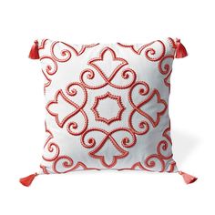 a red and white pillow with tassels on it