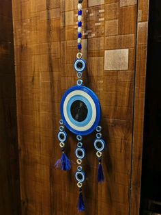 a blue and white clock hanging from the side of a wooden wall with tassels