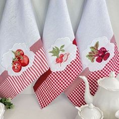 three kitchen towels hanging on the wall next to teapots and other items in front of them