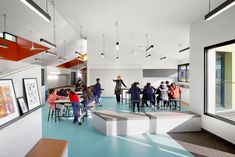 a group of people sitting at tables in a room with blue floors and white walls