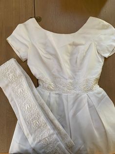 a white dress and leggings sitting on top of a wooden floor