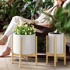 a woman sitting in a chair next to two planters with plants on them,