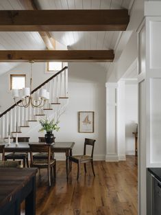 a dining room table with chairs and a chandelier hanging from it's ceiling