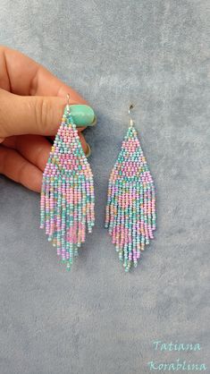 a pair of pink and blue beaded earrings with tassels hanging from them