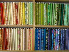 a book shelf filled with lots of different colored fabrics