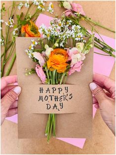 two hands holding a card that says happy mother's day with flowers on it