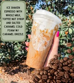 a woman holding up a cup of coffee in front of some coffee beans with the words ice shaker whole milk, toffe nut syrup and salted caramel cold