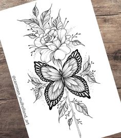 a black and white drawing of a butterfly with flowers on its wings, sitting on a wooden table