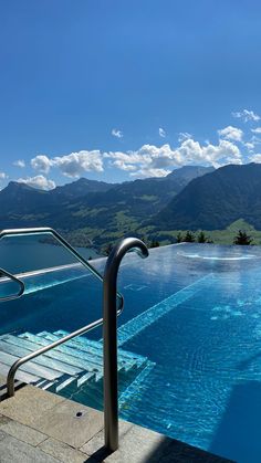 an empty swimming pool with mountains in the backgroud and blue skies above it