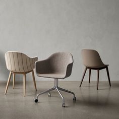 three different chairs sitting next to each other on top of a cement floor in front of a white wall