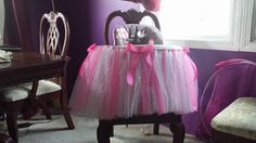 a pink and white tulle skirted chair in front of a window with purple walls