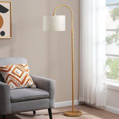 a living room with a chair, lamp and pictures hanging on the wall above it