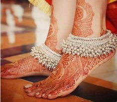 the legs and feet of a woman with henna tattoos on their feet are adorned with jewels