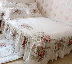 a bed with pink flowers and ruffled bedspread on top of it in a bedroom