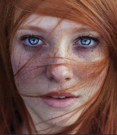 a woman with freckled hair and blue eyes looking at the camera, close up