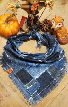 an assortment of fall decorations including scarecrows, pumpkins and scarves on a wooden table