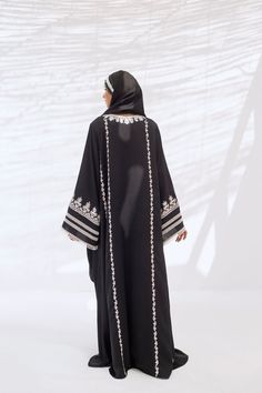 A classic loose-fitting silhouette crafted from silky soft black crepe with contrasting embroidery accents. Paired with a matching georgette scarf to create a look that is truly timeless and elegant. Elegant Black Abaya With Floral Embroidery, Elegant Dresses With Embroidered Border For Traditional Ceremonies, Evening Kaftan With Floral Embroidery, Elegant Floral Embroidered Kaftan For Evening, Elegant Floral Embroidery Kaftan For Evening, Elegant Floral Embroidered Evening Kaftan, Black Embroidered Abaya For Wedding, Black Abaya With Floral Embroidery, Black Embroidered Wedding Abaya