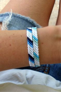 a close up of a person's arm wearing a bracelet with blue and white beads