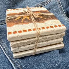 a stack of stone coasters sitting on top of a pair of jeans