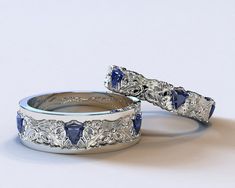 two silver wedding bands with blue stones on each band and filigrees in the middle