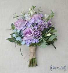 a bouquet of purple flowers is tied to a wall