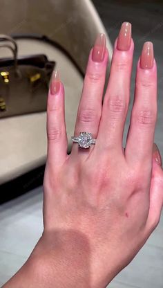 a woman's hand with a ring on it and a purse in the background